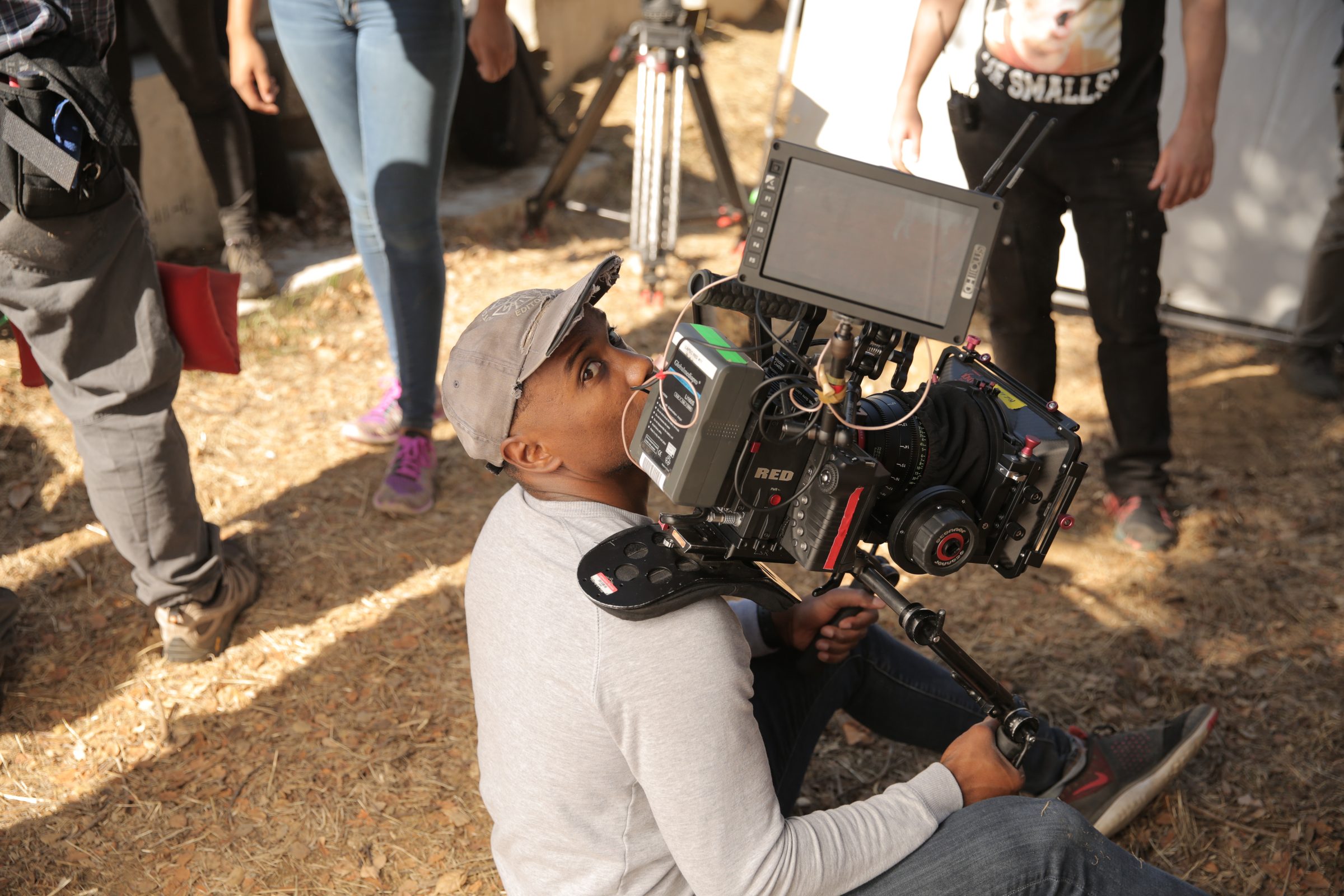 Isaiah operating a RED camera from a low angle on location